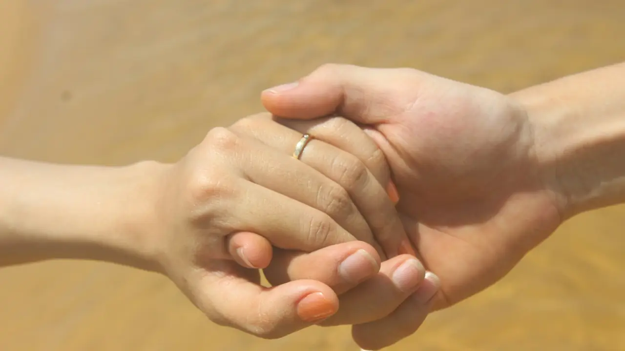 Twee mensen houden elkaars hand vast