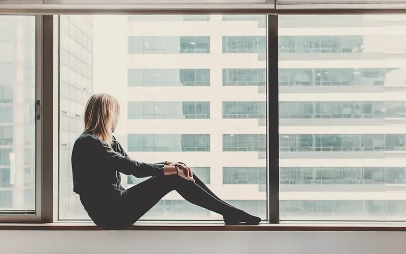 Jonge vrouw bij een groot raam