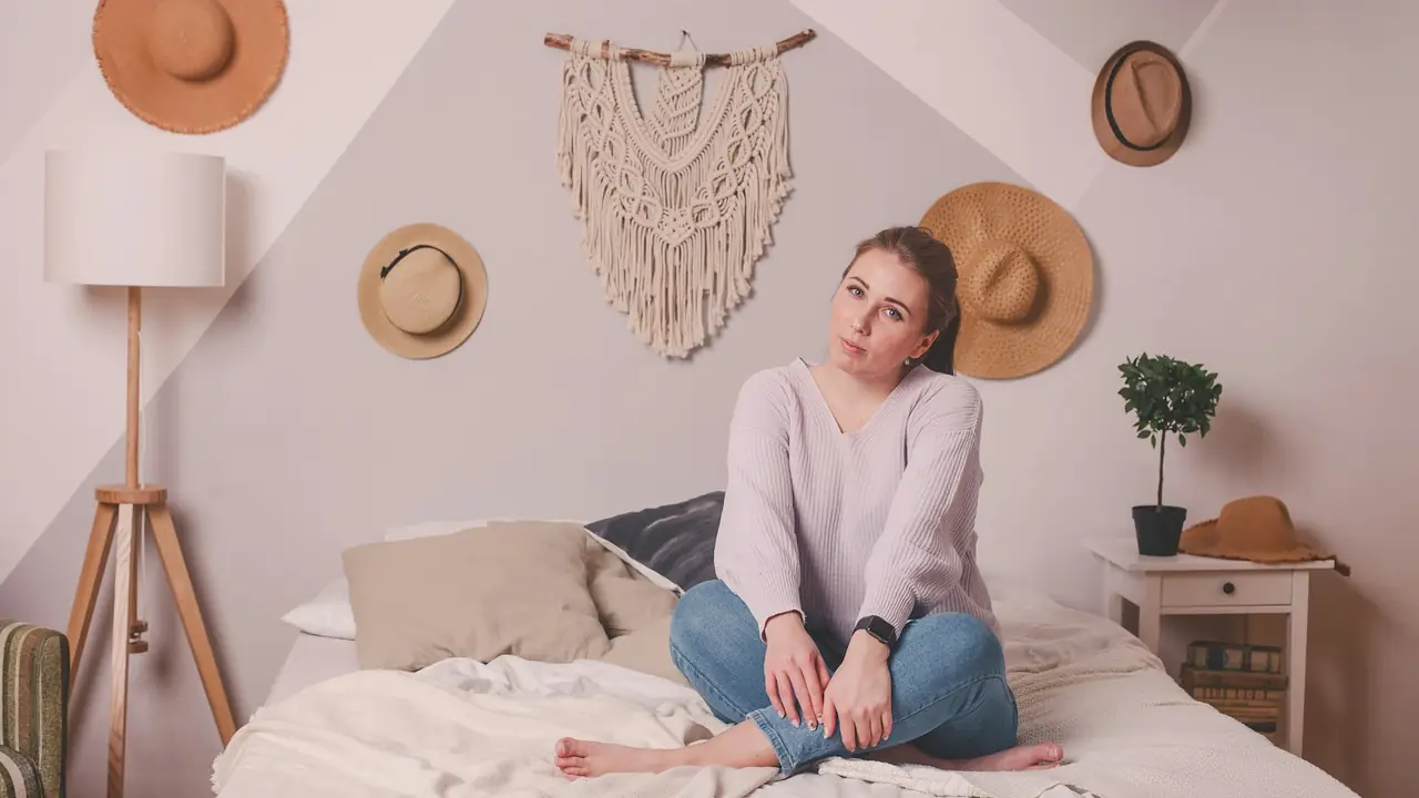 Vrouw zit rustig op haar bed in een lichte slaapkamer