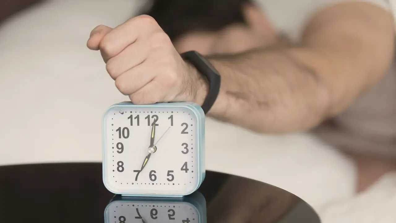 Hand op een wekker in bed