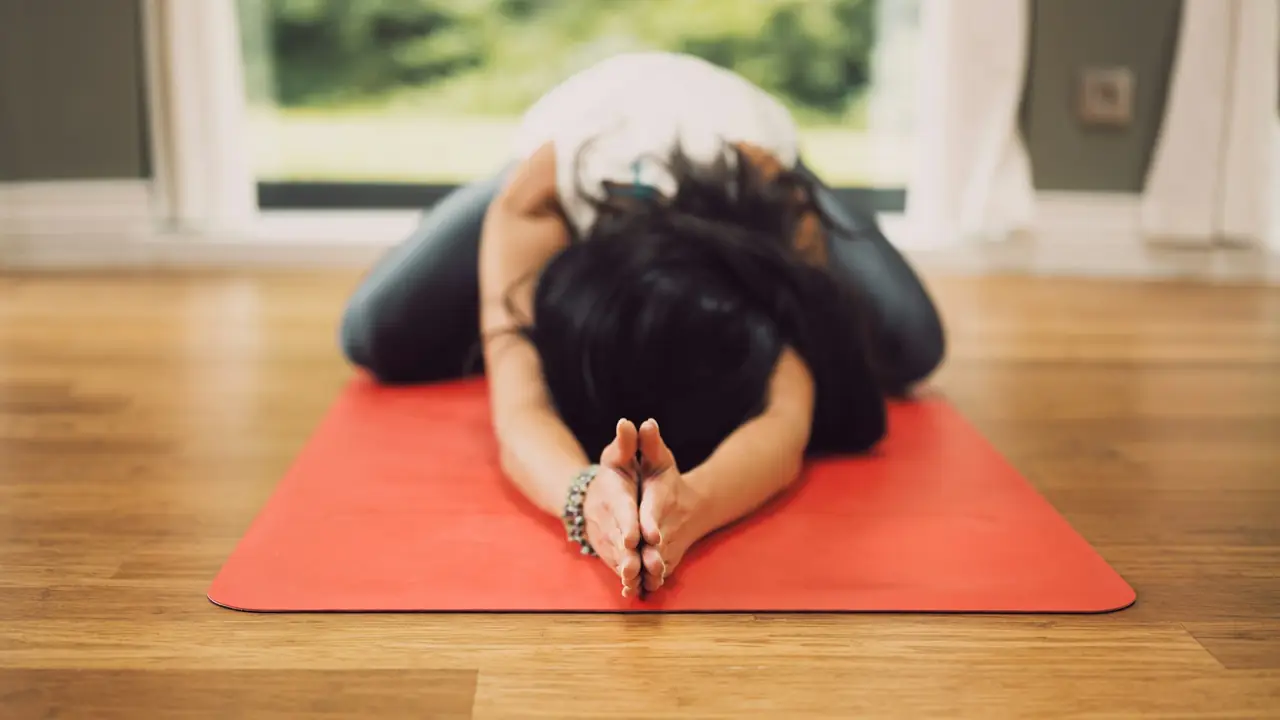 Vrouw doet een rustige rekoefening op een yogamat