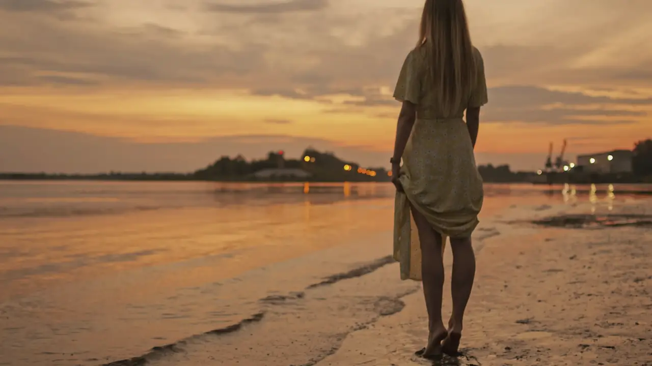 Vrouw die bij zonsondergang langs het strand loopt