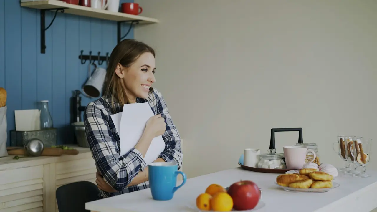 Vrouw leest een brief aan de keukentafel