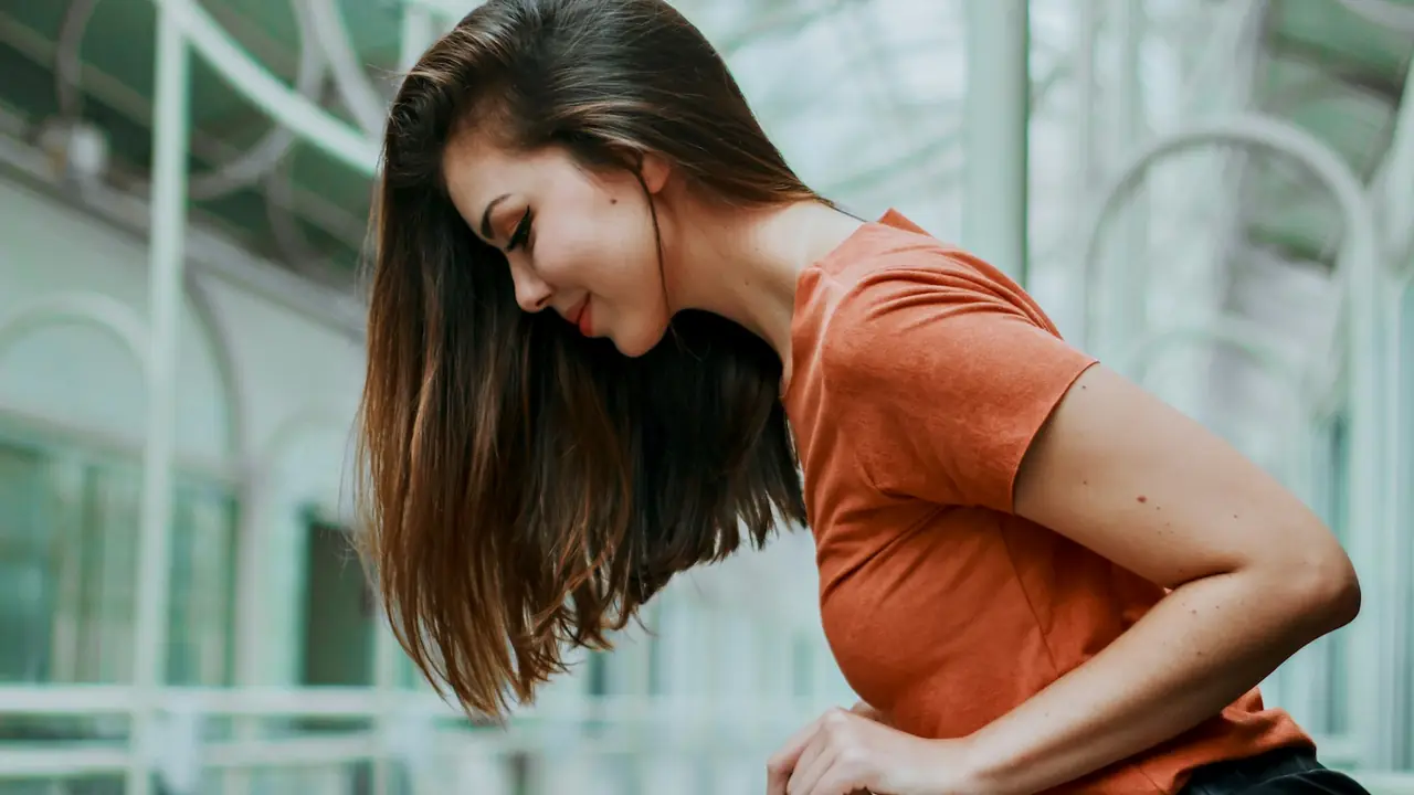 Vrouw houdt haar hand op haar buik bij buikpijn