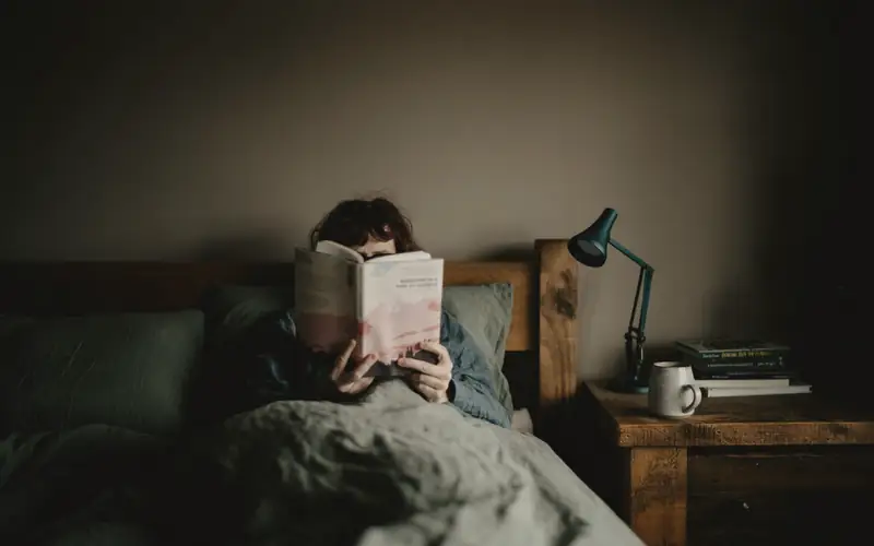 Iemand die in bed leest bij een lamp