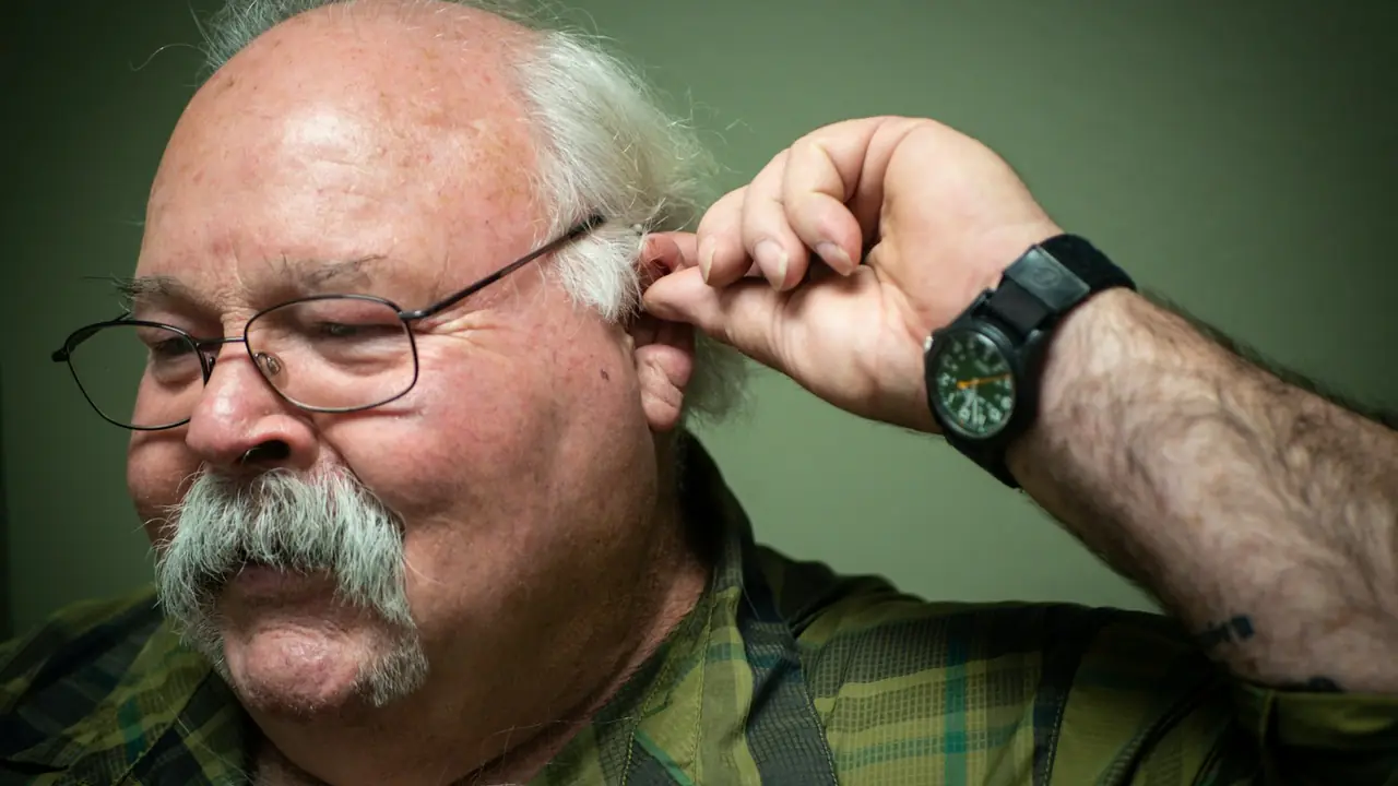 Man met bril houdt zijn hand bij zijn oor