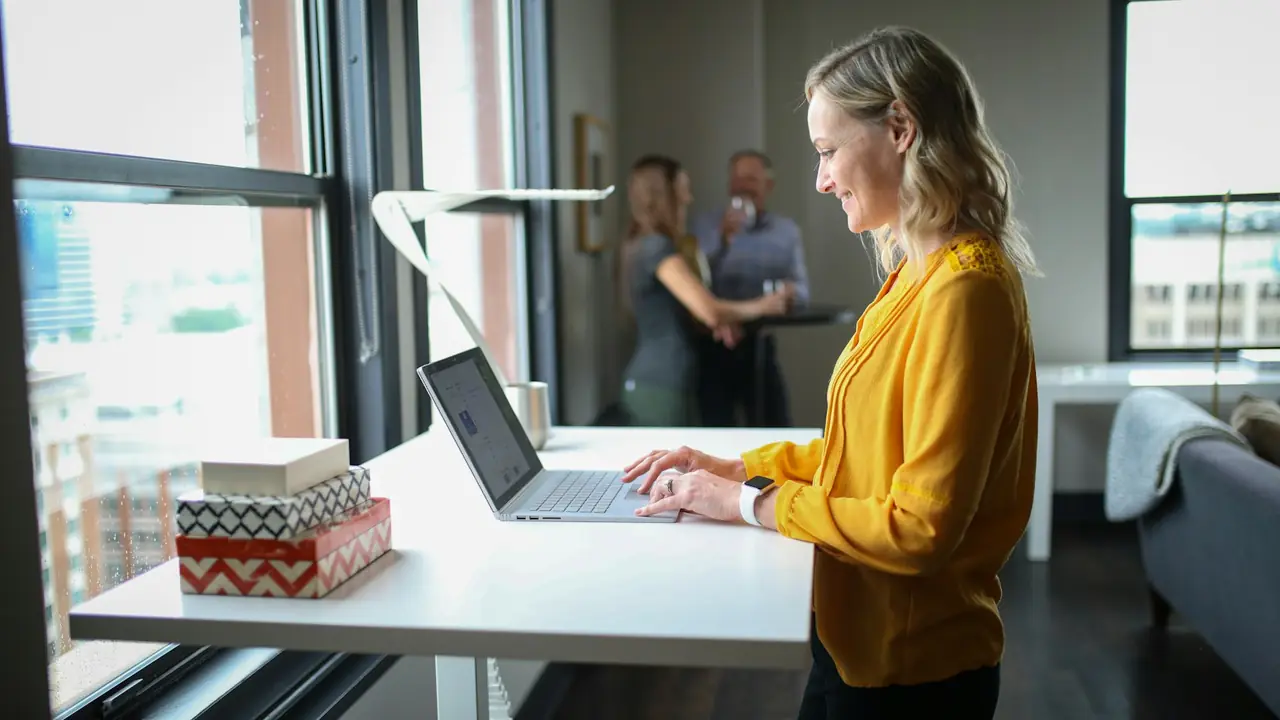 Vrouw werkt staand aan een bureau bij het raam